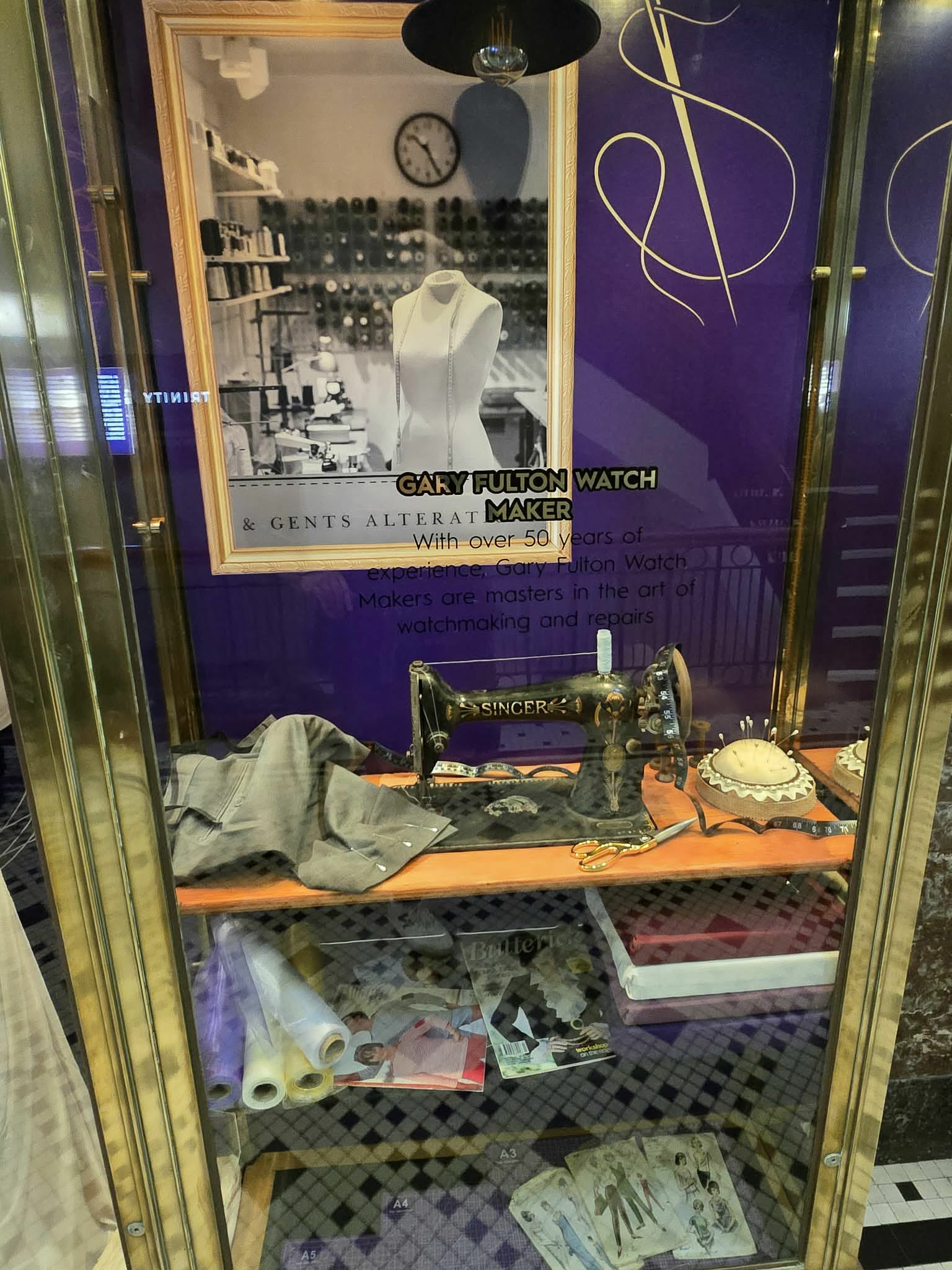 Tailor cabinet detail with sewing machine, garment work, and textile references